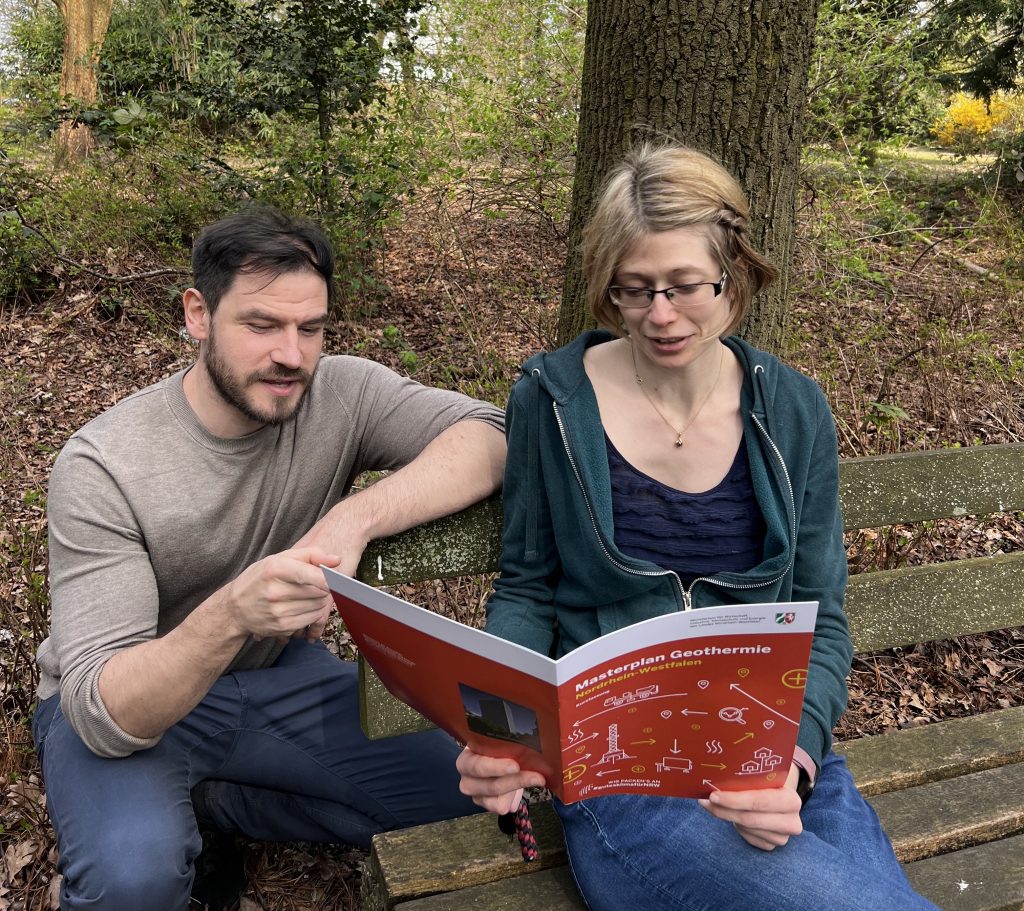 ein Mann und eine Frau lesen eine Broschüre, den Masterplan Geothermie NRW
