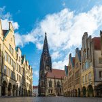 Prinzipalmarkt in Münster, Hausfassaden und im Hintergrund die Lambertikirche, blauer Himmel mit Schäfchenwolken